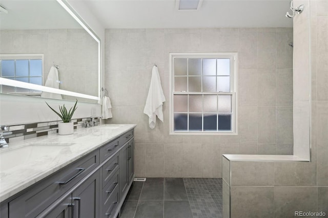 bathroom with vanity, a healthy amount of sunlight, tile walls, and tile patterned floors