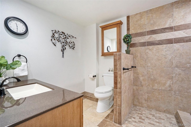 bathroom featuring vanity, tile patterned flooring, toilet, and a tile shower