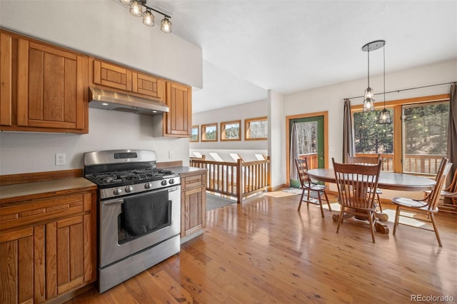 1740 County Road 72, Bailey, CO 80421 - kitchen with light wood-style floors, brown cabinetry, stainless steel range with gas stovetop, and under cabinet range hood