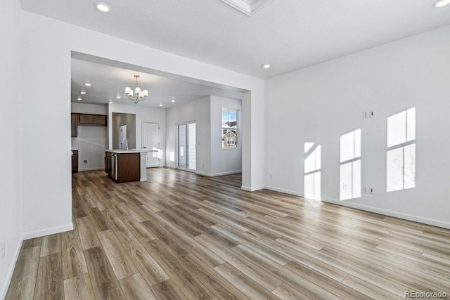 unfurnished living room featuring sink, hardwood / wood-style floors, and a notable chandelier