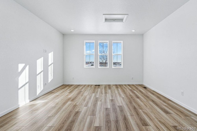 empty room featuring a textured ceiling and light hardwood / wood-style flooring