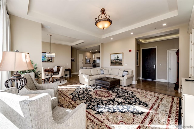 living room with a notable chandelier, dark hardwood / wood-style floors, and a raised ceiling