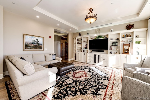 living room with wood-type flooring and a raised ceiling