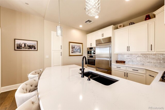 kitchen with tasteful backsplash, dark hardwood / wood-style flooring, appliances with stainless steel finishes, a kitchen bar, and pendant lighting