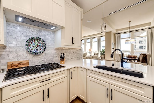 kitchen with stainless steel gas cooktop, kitchen peninsula, custom range hood, sink, and tasteful backsplash