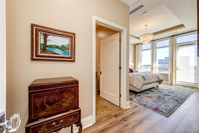 hallway with light hardwood / wood-style flooring and a tray ceiling