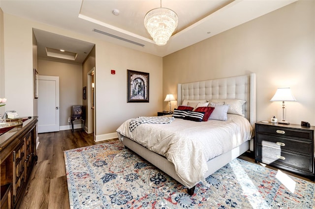 bedroom featuring an inviting chandelier, dark hardwood / wood-style floors, and a raised ceiling