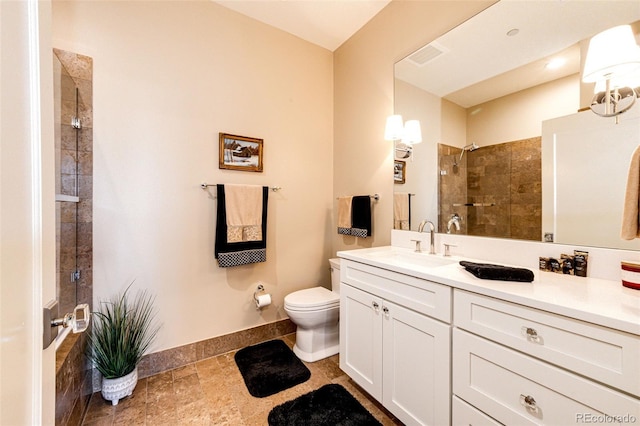 bathroom featuring vanity, tiled shower, and toilet