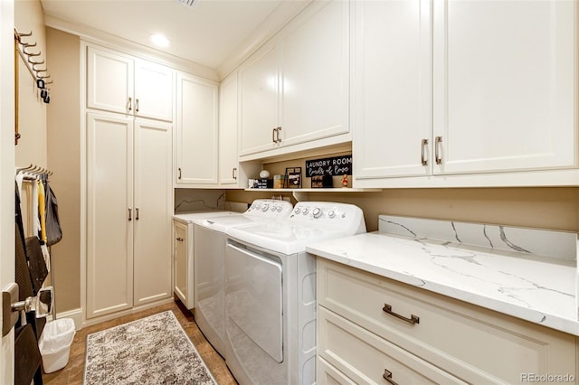 laundry room featuring wood-type flooring, washing machine and dryer, and cabinets