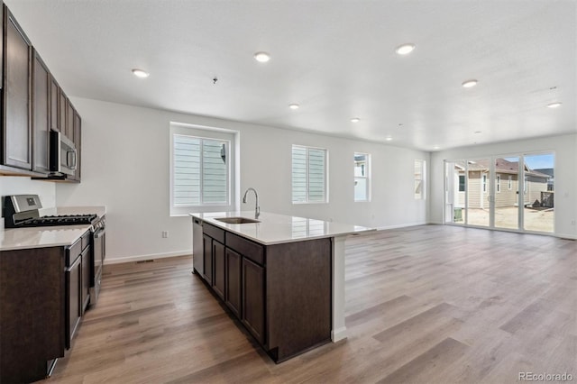 9662 Cathay St, Commerce City, CO 80022 - kitchen with dark brown cabinets, a sink, stainless steel appliances, light wood-style flooring, and baseboards
