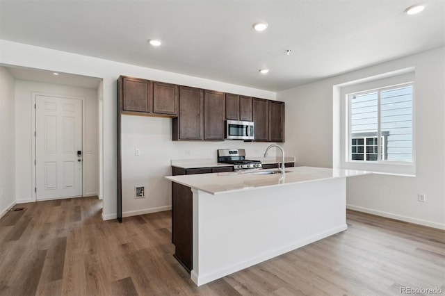 9662 Cathay St, Commerce City, CO 80022 - kitchen with light countertops, dark brown cabinets, a sink, light wood-type flooring, and appliances with stainless steel finishes