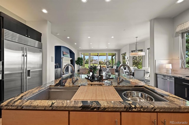 1287 Buffalo Ridge Rd, Castle Pines, CO 80108 - kitchen with stainless steel appliances, a sink, a center island with sink, dark stone countertops, and recessed lighting