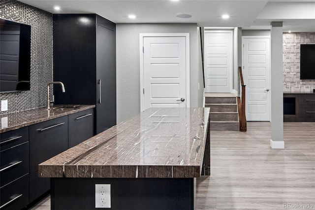 3439 Uinta St, Denver, CO 80238 - kitchen featuring a sink, light wood-type flooring, a kitchen island, light stone countertops, and backsplash