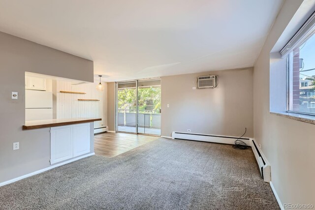 unfurnished room featuring a baseboard heating unit, a wall mounted AC, and light carpet