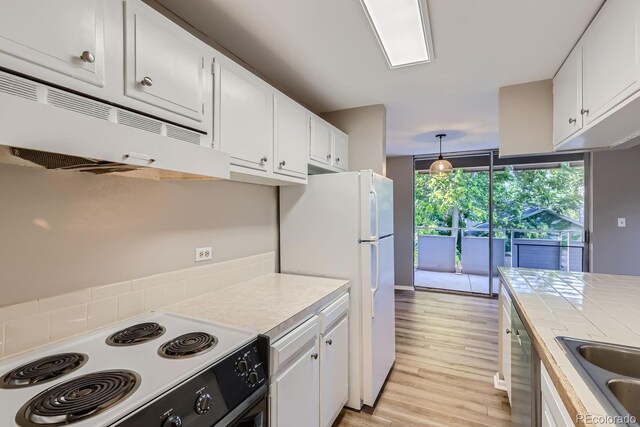 kitchen with hanging light fixtures, white cabinets, light wood-type flooring, sink, and range