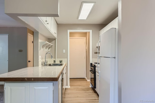 kitchen featuring light wood-type flooring, sink, white fridge, white cabinetry, and electric range oven