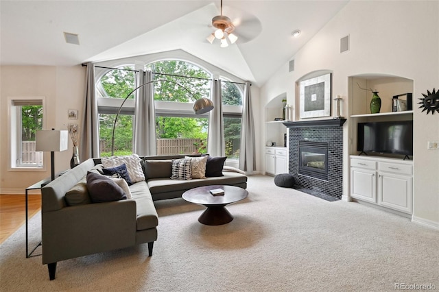 3144 Stevens Cir N, Erie, CO 80516 - living room with a tiled fireplace, a ceiling fan, lofted ceiling, built in features, and light colored carpet