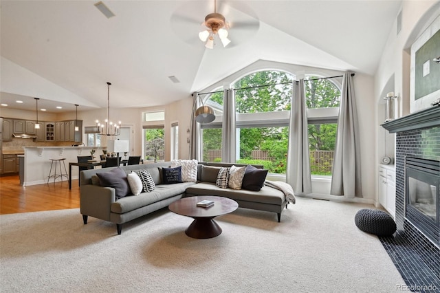 3144 Stevens Cir N, Erie, CO 80516 - living room featuring light colored carpet, a fireplace, high vaulted ceiling, a chandelier, and a ceiling fan