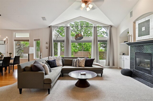 3144 Stevens Cir N, Erie, CO 80516 - living room featuring plenty of natural light, a ceiling fan, built in shelves, a tile fireplace, and vaulted ceiling