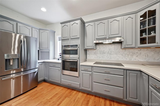 3144 Stevens Cir N, Erie, CO 80516 - kitchen with appliances with stainless steel finishes, gray cabinets, under cabinet range hood, glass insert cabinets, and decorative backsplash