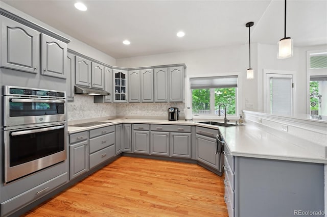 3144 Stevens Cir N, Erie, CO 80516 - kitchen with gray cabinets, stainless steel double oven, under cabinet range hood, black electric stovetop, and backsplash