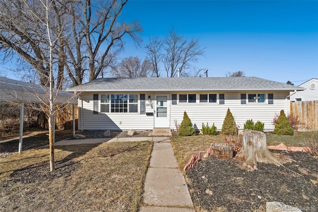 ranch-style house featuring fence and roof with shingles