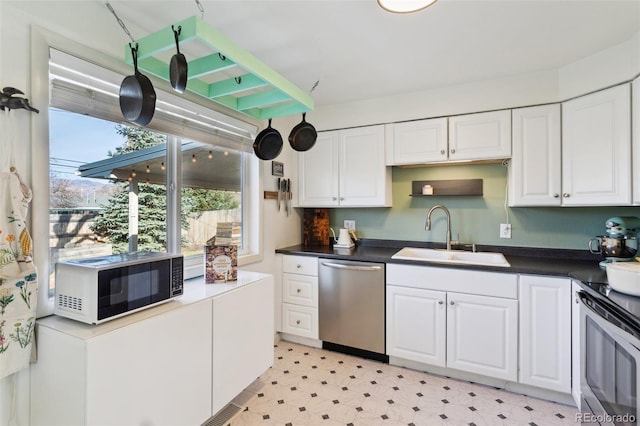 kitchen featuring white cabinetry, light floors, appliances with stainless steel finishes, and a sink