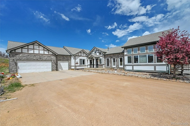 view of front facade featuring a garage, driveway, and stone siding