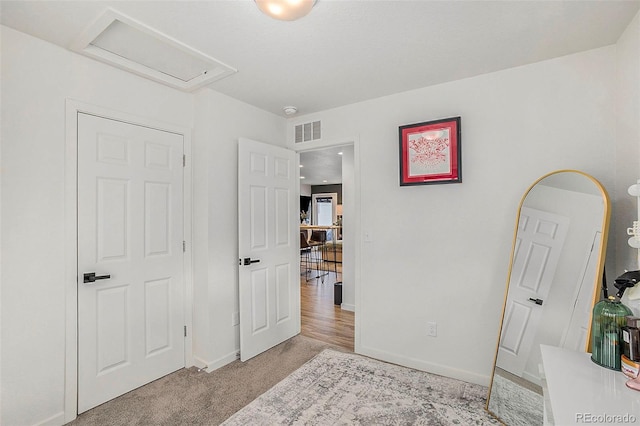 carpeted bedroom featuring baseboards, visible vents, and attic access