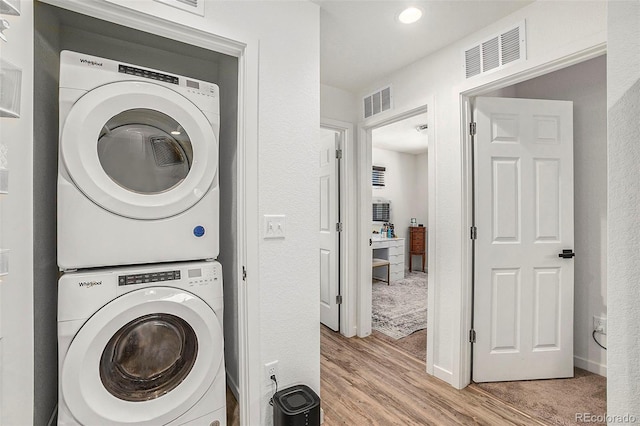 laundry area featuring laundry area, light wood-style flooring, visible vents, and stacked washer / dryer