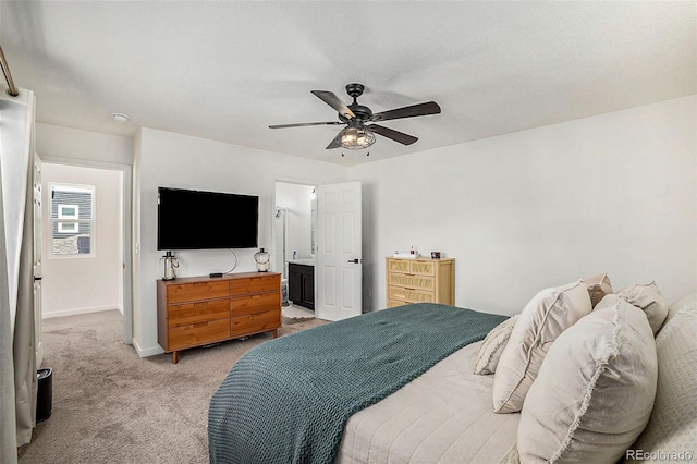 bedroom featuring light colored carpet, ceiling fan, ensuite bath, and baseboards