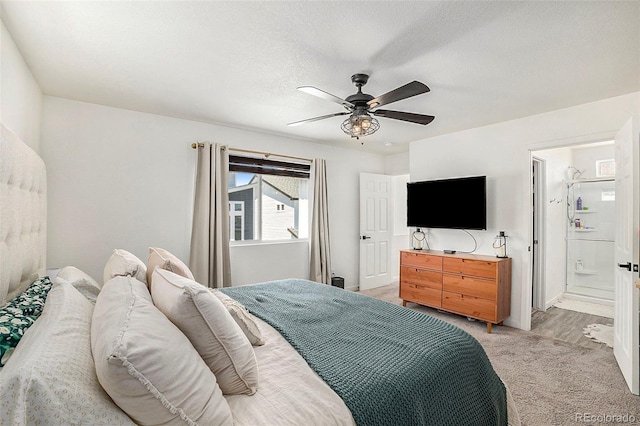 bedroom featuring light carpet, ceiling fan, a textured ceiling, and ensuite bathroom