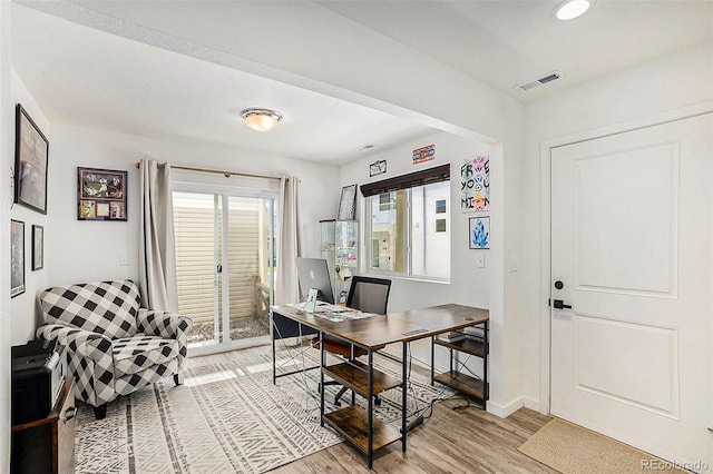 office area featuring light wood-type flooring, visible vents, and baseboards