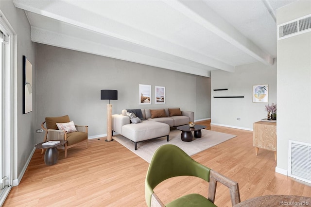 living room featuring baseboards, light wood finished floors, beam ceiling, and visible vents
