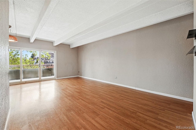 spare room featuring a textured ceiling, baseboards, beam ceiling, and wood finished floors