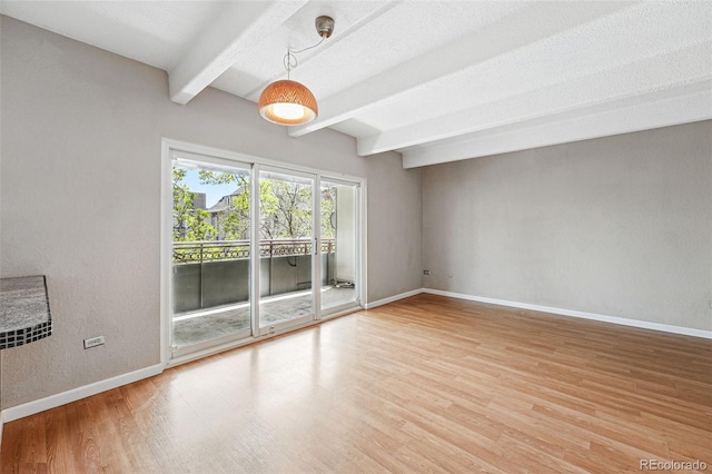 spare room featuring baseboards, beam ceiling, and wood finished floors