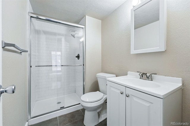 full bathroom featuring a textured wall, vanity, toilet, tile patterned floors, and a stall shower