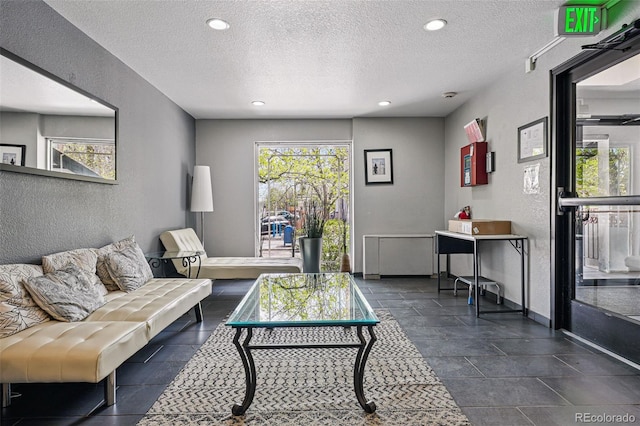 living area featuring recessed lighting, a textured ceiling, and a textured wall