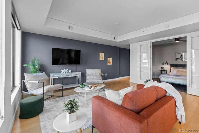 living room featuring wood finished floors, a raised ceiling, and baseboards