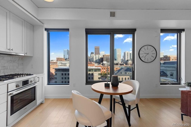 dining area featuring light wood-style floors, a skyline view, and baseboards