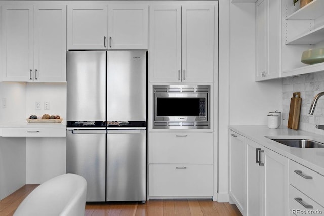 kitchen featuring a sink, appliances with stainless steel finishes, light countertops, and white cabinetry