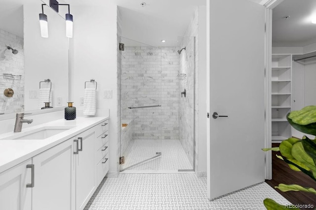 bathroom with a shower stall, vanity, and a spacious closet