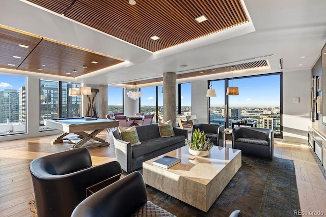living area with billiards table, floor to ceiling windows, wood-type flooring, and a raised ceiling