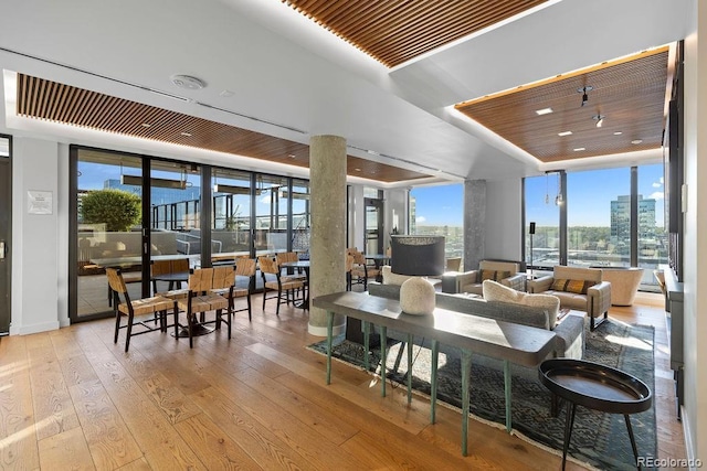 living area featuring wood-type flooring, a raised ceiling, wooden ceiling, expansive windows, and baseboards