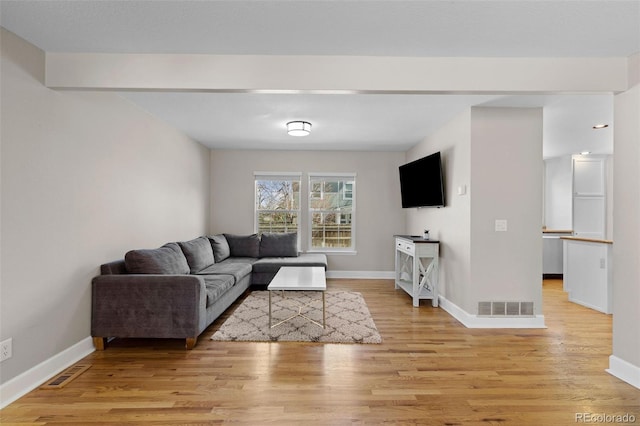 living room with visible vents, light wood-style floors, and baseboards