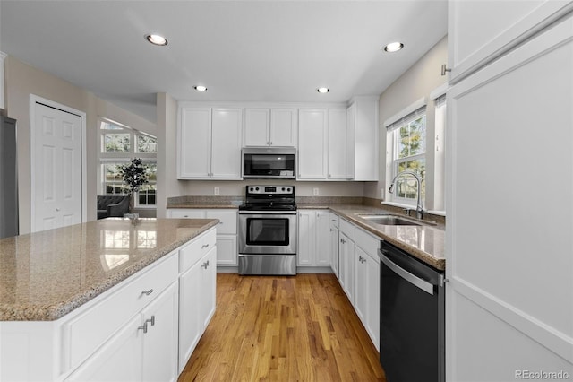 kitchen featuring a sink, recessed lighting, appliances with stainless steel finishes, white cabinets, and light stone countertops