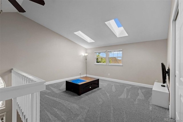 interior space with vaulted ceiling, carpet, baseboards, and ceiling fan