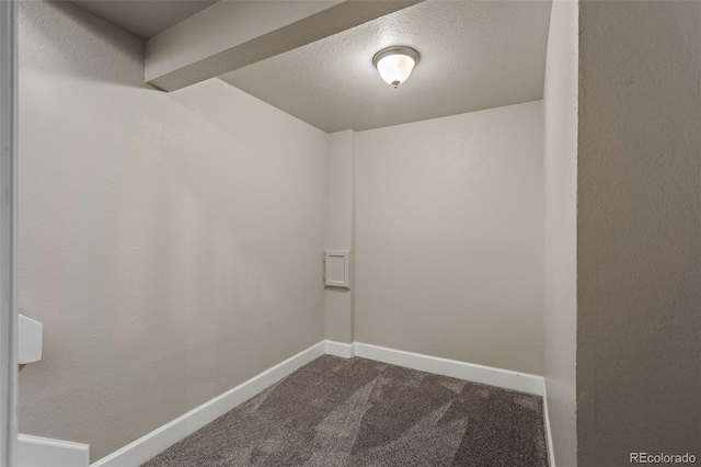 spare room featuring baseboards, dark colored carpet, and a textured ceiling