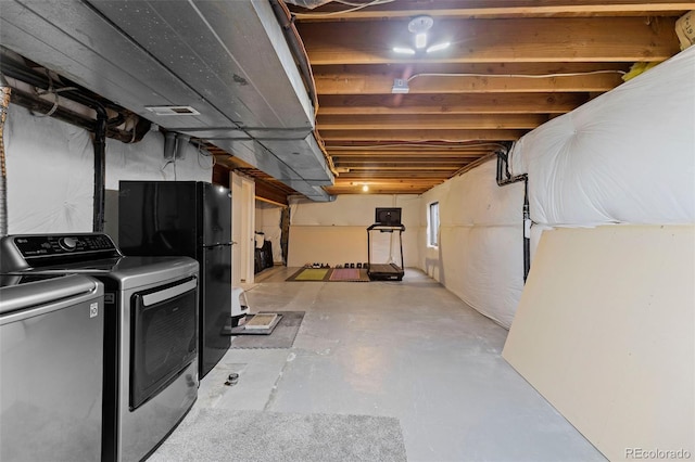 unfinished basement with visible vents, washer and clothes dryer, and freestanding refrigerator