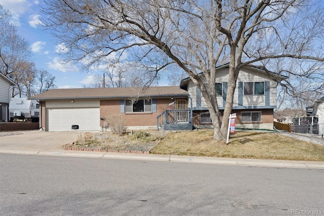 split level home with a garage, brick siding, and driveway